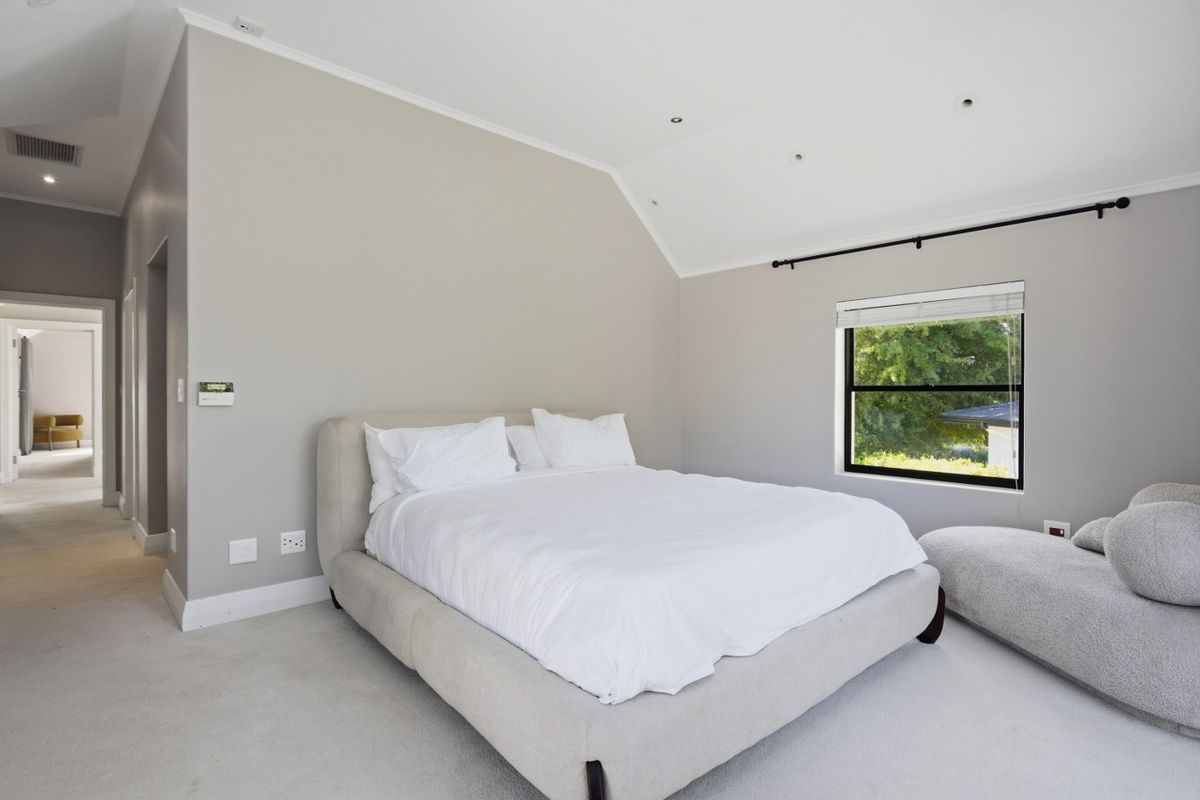 A spacious bedroom featuring high vaulted ceilings, neutral wall tones, and large windows that provide ample natural light.