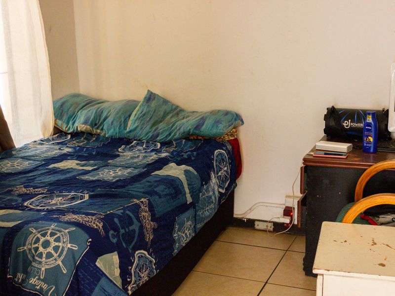 A bedroom featuring tiled flooring and neutral wall finishes, requiring minor cosmetic updates to improve the overall presentation.