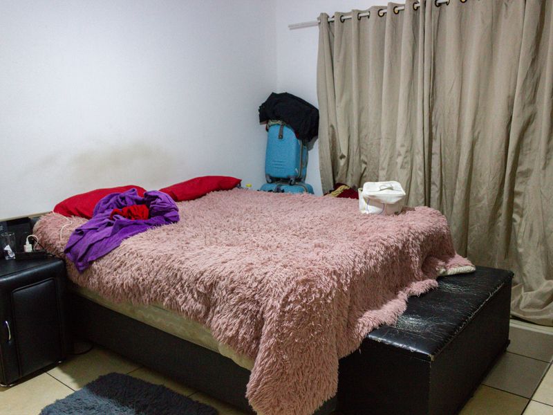 A bedroom featuring tiled flooring and a curtain rail, providing a functional space for rest.