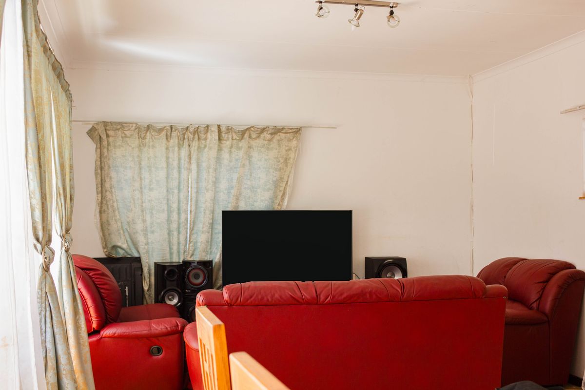 A living room space featuring neutral walls and a ceiling-mounted spotlight track.