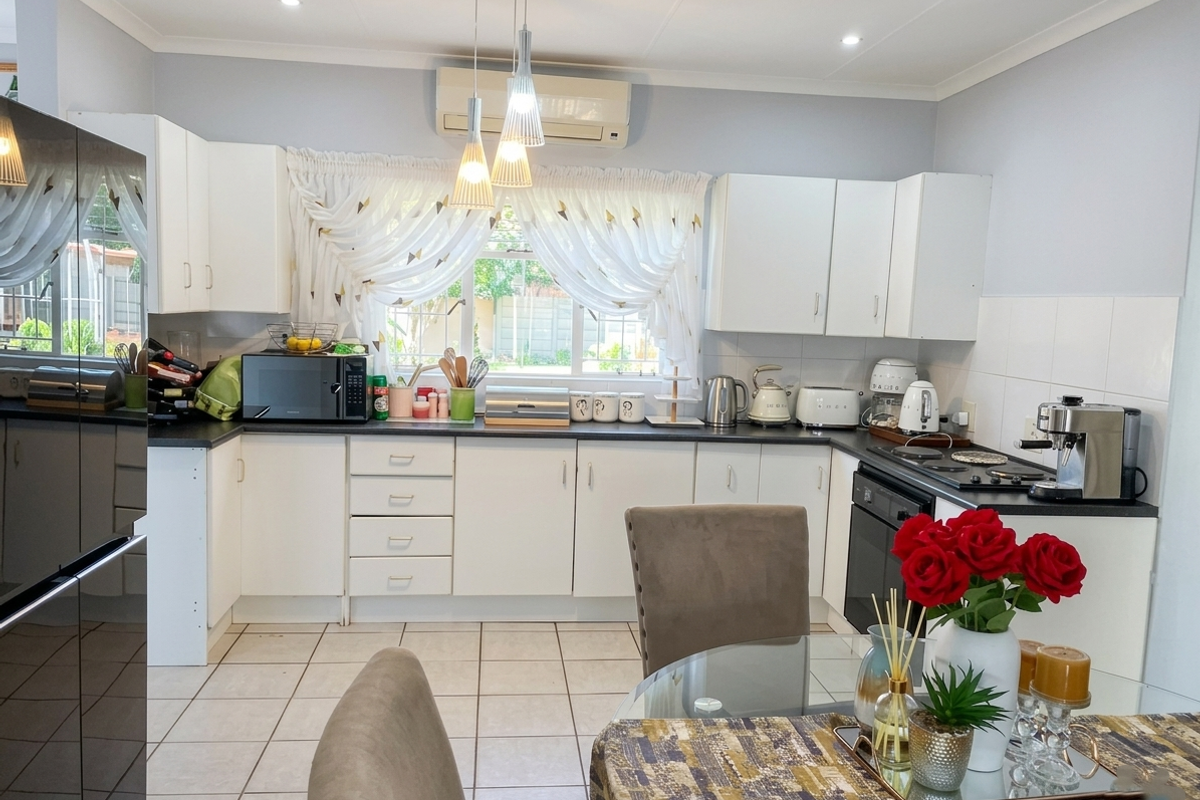 A functional kitchen featuring white cabinetry, dark countertops, tiled flooring, and integrated appliances, offering a clean and well-maintained workspace.