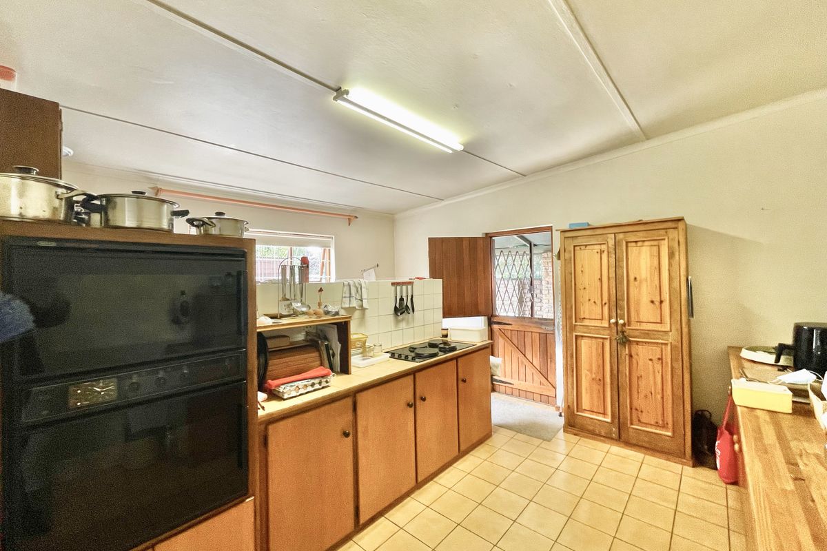 A functional kitchen featuring built-in wooden cabinetry, a wall-mounted oven, a gas hob, and direct access to an exterior door.