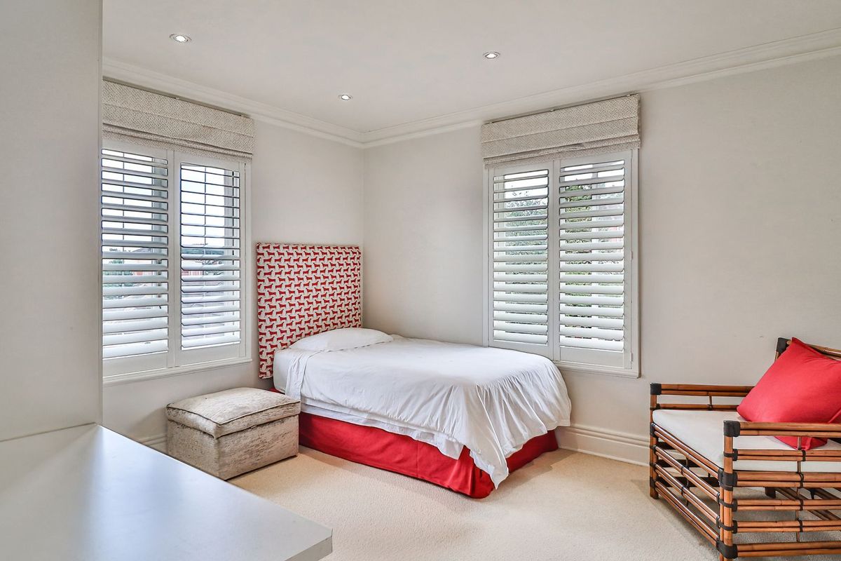 A bright and well-maintained bedroom featuring plantation shutters, recessed downlighting, and neutral carpeting, offering a clean and comfortable living space.