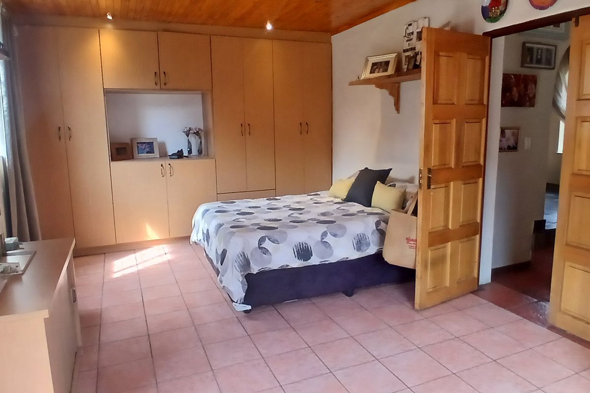 A bedroom featuring built-in wooden cabinetry, tiled flooring, and a timber-paneled ceiling, providing ample storage and a warm aesthetic.