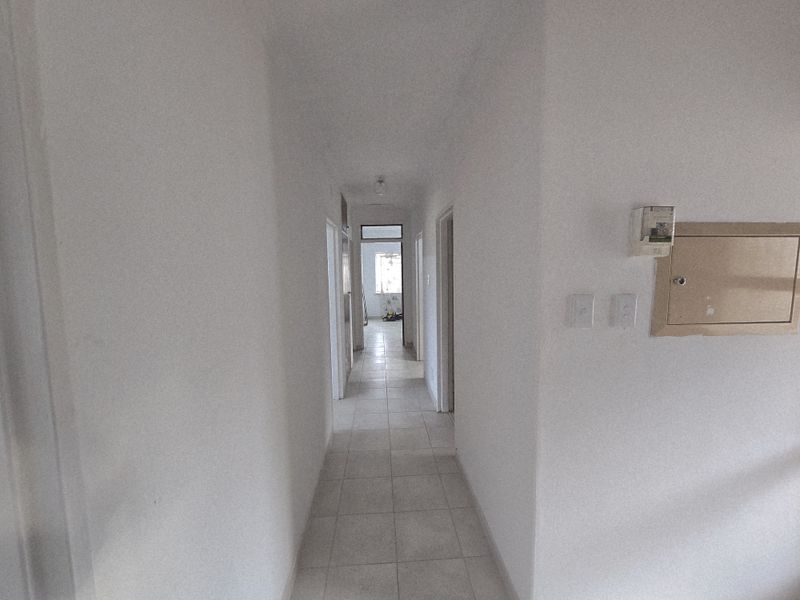 A functional interior hallway featuring neutral floor tiling and multiple doorways leading to various rooms within the property.