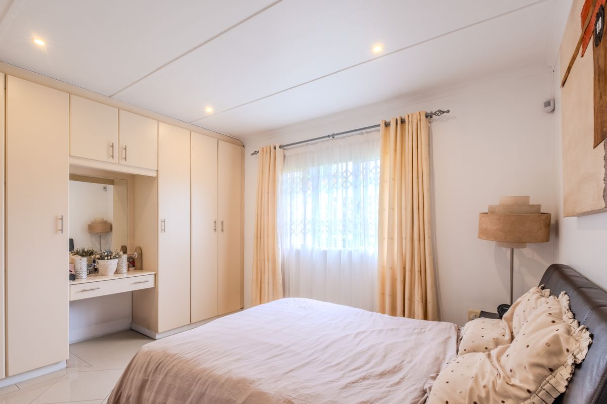 A well-maintained bedroom featuring extensive built-in cabinetry with an integrated vanity, recessed lighting, and tiled flooring.
