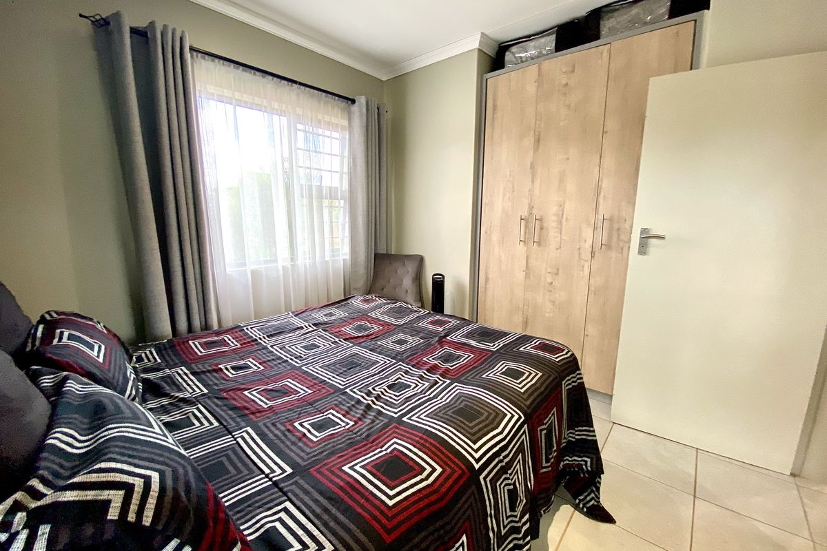 A well-maintained bedroom featuring tiled flooring, neutral wall tones, and a functional built-in wardrobe with wood-grain finish.