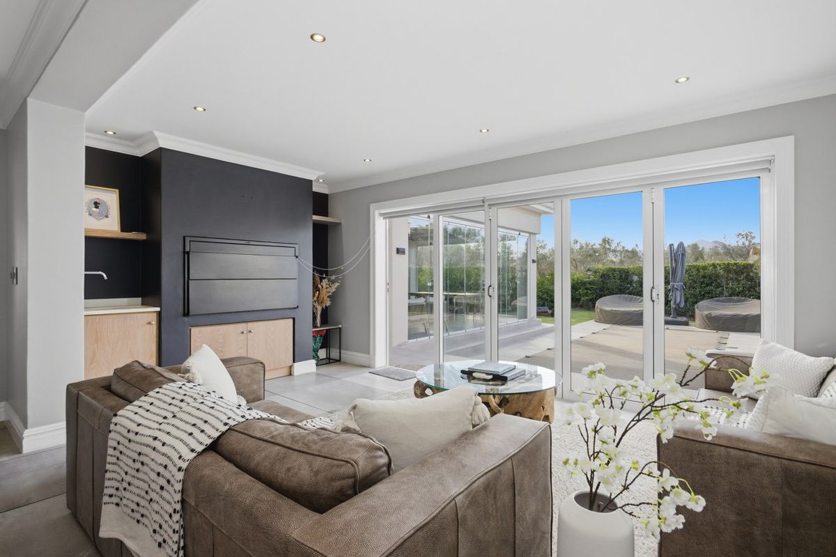Spacious living area featuring modern recessed lighting, built-in cabinetry, and large sliding glass doors providing seamless access to the outdoor patio and garden.