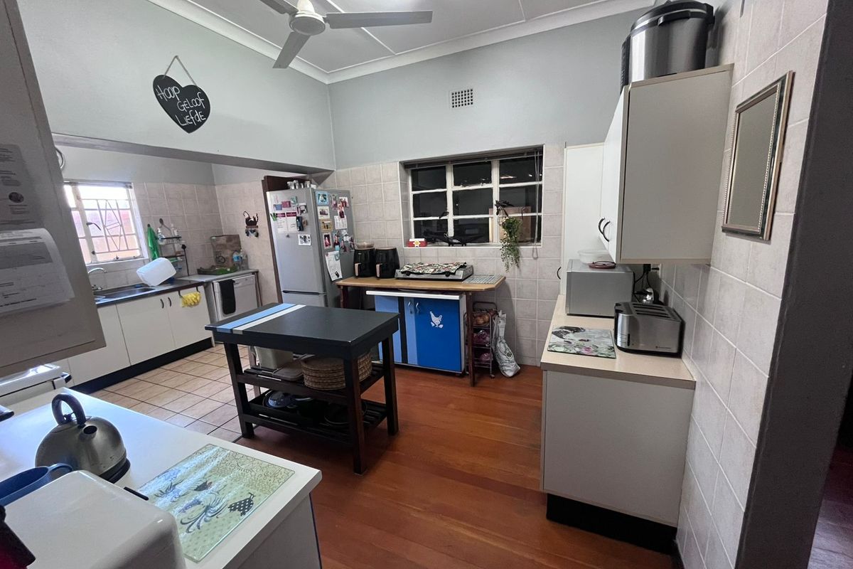 A functional kitchen featuring tiled splashbacks, built-in cabinetry, and a ceiling fan, offering a practical layout with ample counter space.