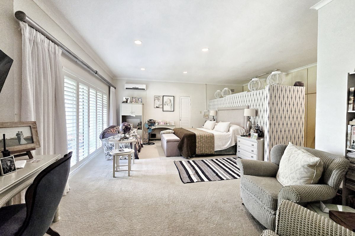 Spacious bedroom featuring recessed lighting, wall-mounted air conditioning unit, and large sliding glass doors with plantation shutters leading to an outdoor area.