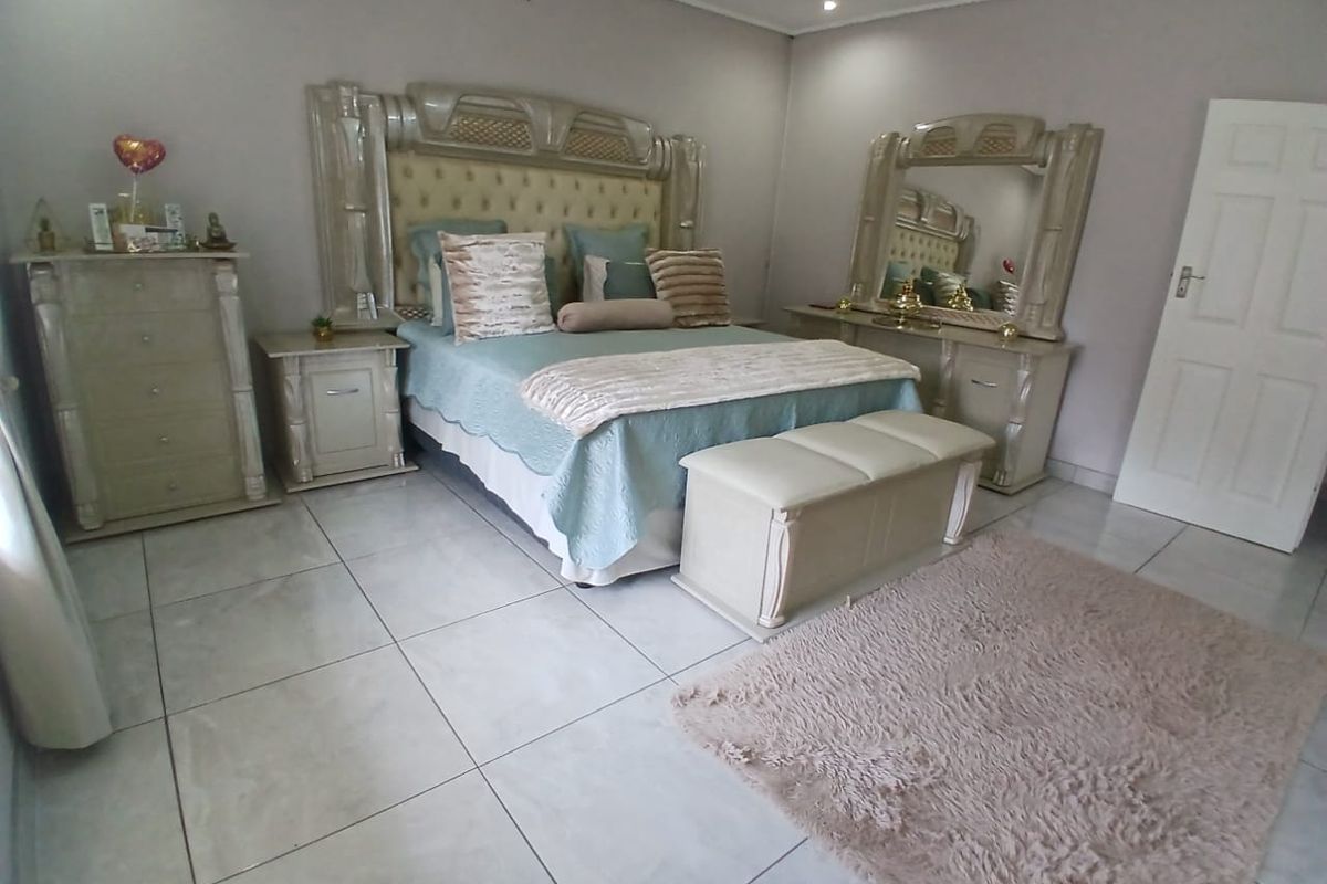 A spacious bedroom featuring light-colored floor tiles, neutral wall tones, and recessed ceiling lighting, providing a clean and well-maintained living space.