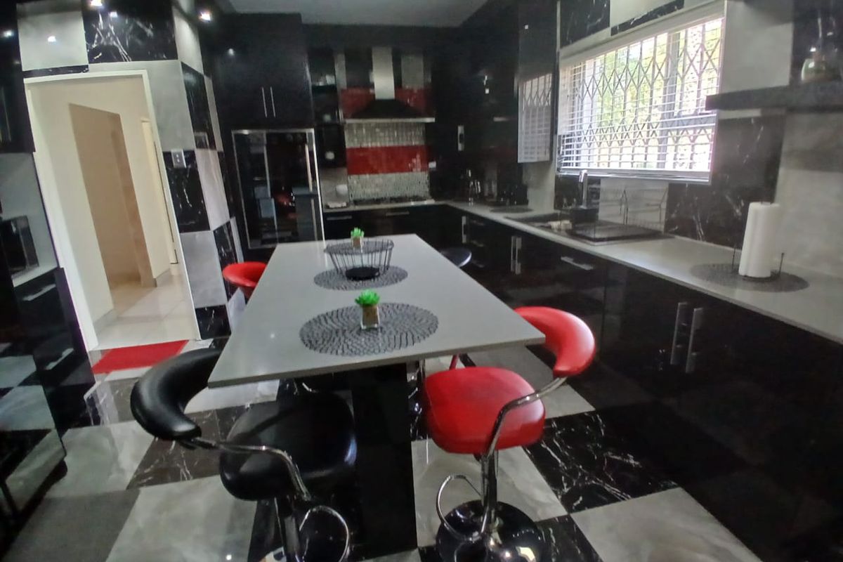 Modern kitchen featuring high-gloss black cabinetry, a central island, tiled flooring, and integrated appliances with a bold, high-contrast aesthetic.