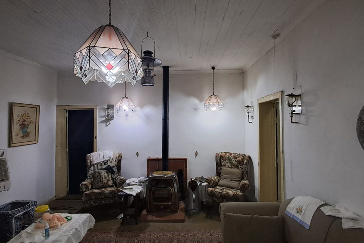 A living room featuring a central wood-burning stove, beadboard ceiling, and multiple vintage-style pendant light fixtures.
