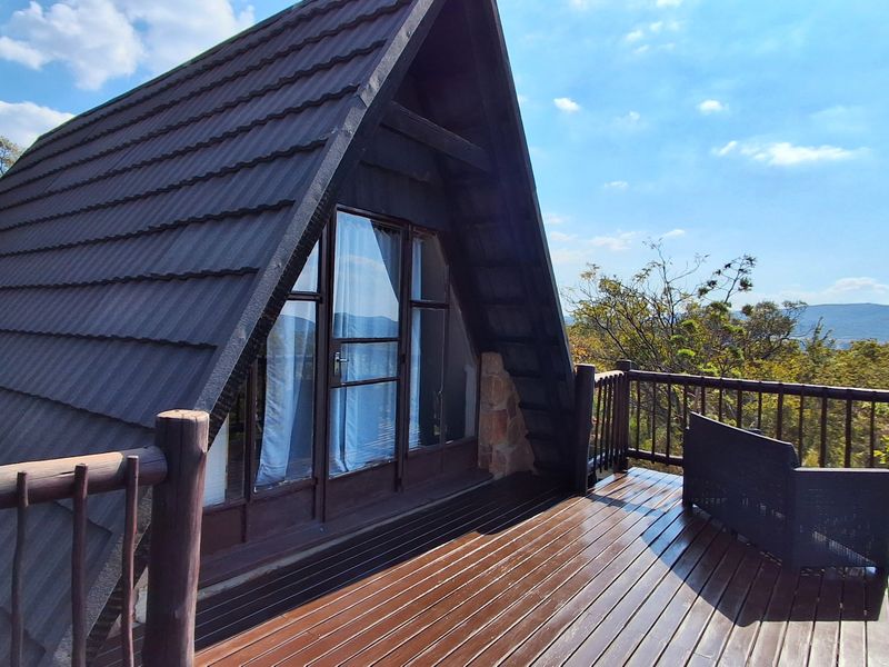 An elevated timber balcony attached to an A-frame townhouse, featuring a wooden balustrade and scenic views of the surrounding landscape.