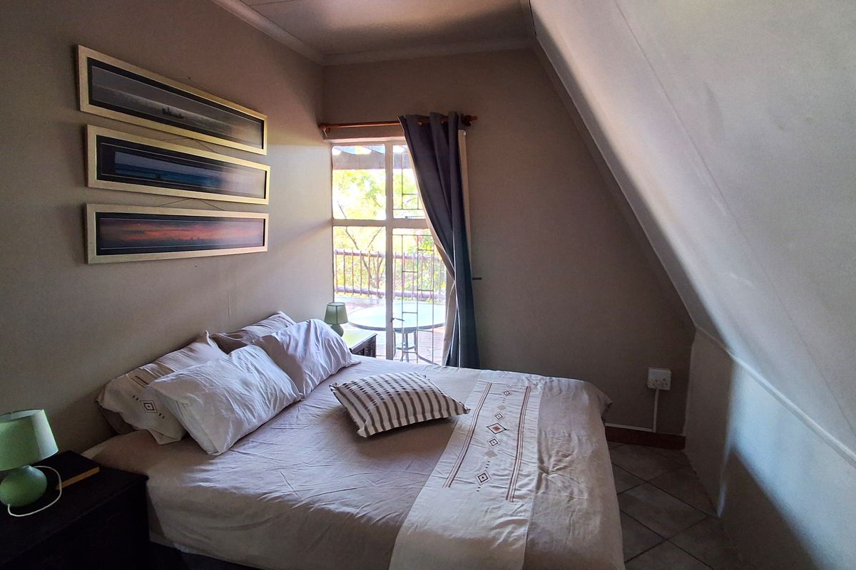 Cozy bedroom featuring a sloped ceiling, tiled flooring, and direct access to a private balcony through a sliding door.