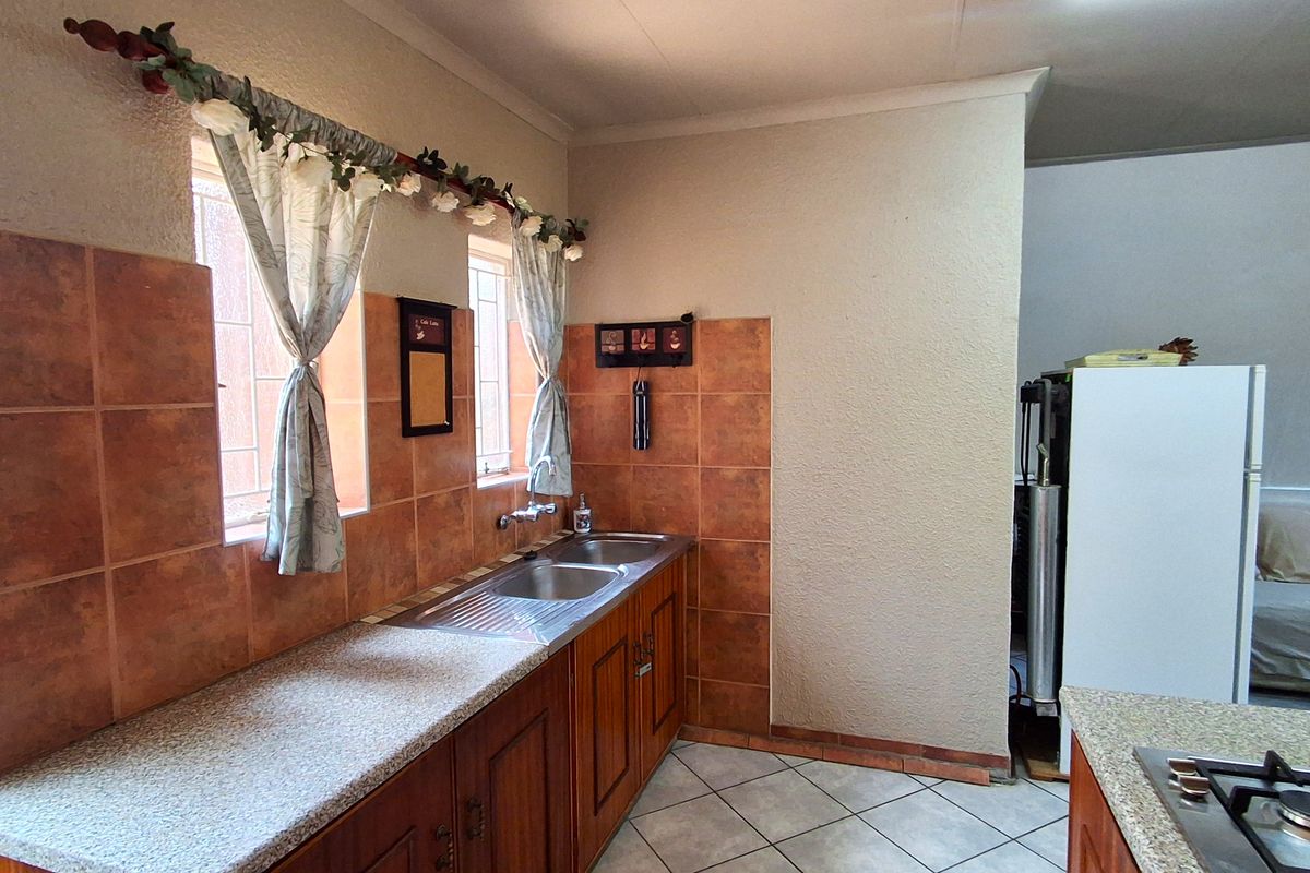 A functional kitchen featuring wooden cabinetry, laminate countertops, ceramic wall tiling, and a built-in gas hob with oven.