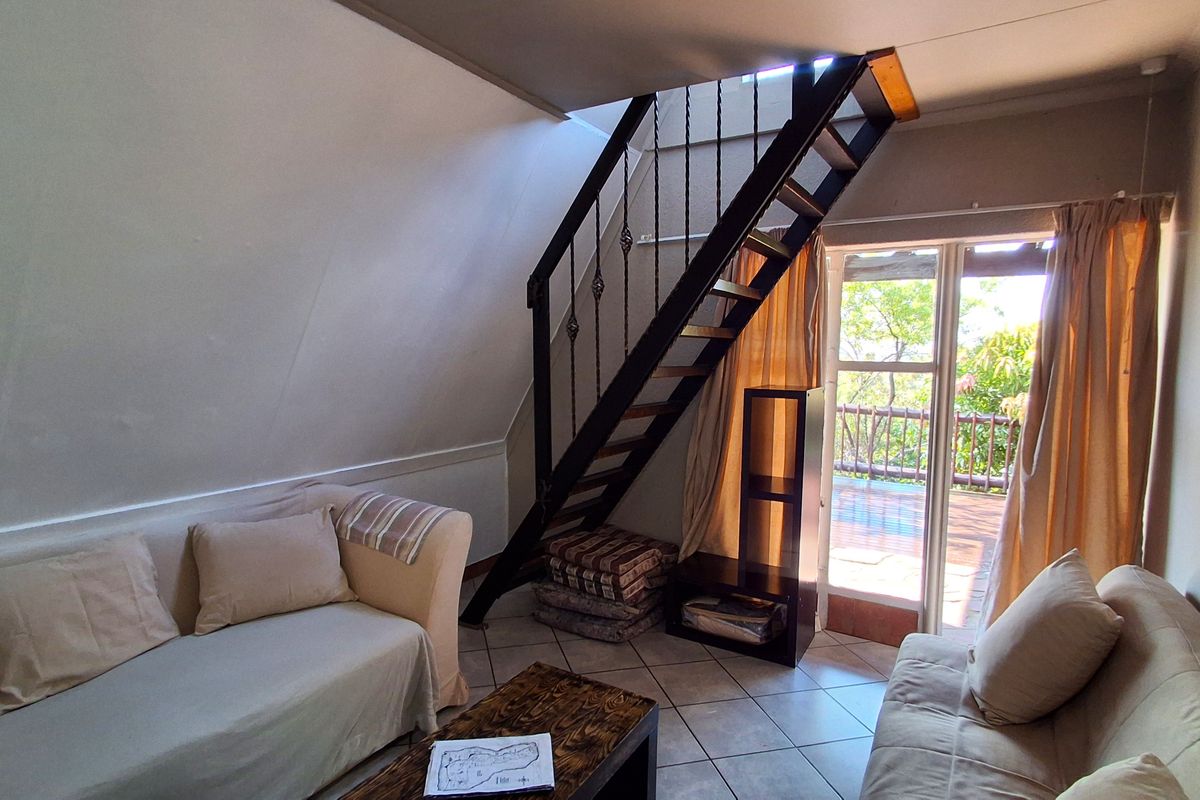 A living room featuring a metal staircase leading to an upper level, tiled flooring, and direct access to an outdoor patio area.