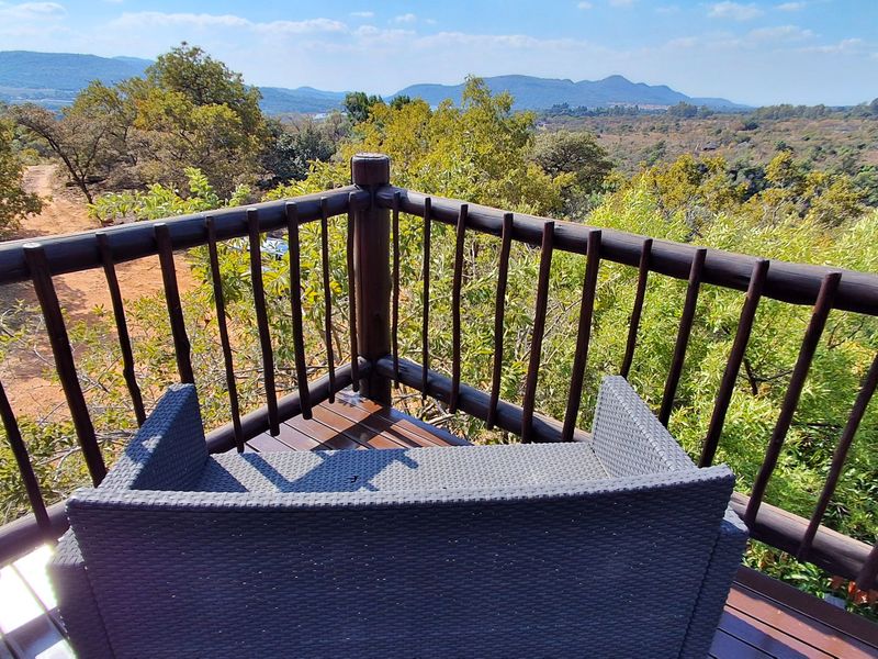 An elevated timber balcony featuring a rustic wooden balustrade and expansive views of the surrounding natural landscape.