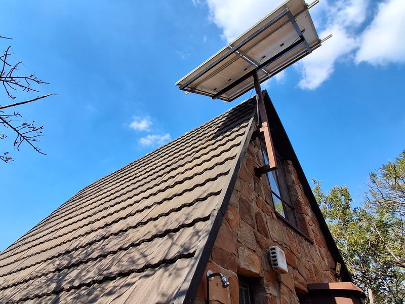 A view of the property's stone-clad exterior featuring a pitched tiled roof and a mounted solar panel system.