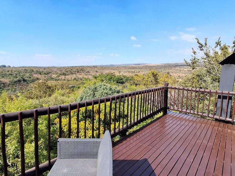 Elevated timber balcony featuring a built-in fireplace and expansive views of the surrounding natural landscape.