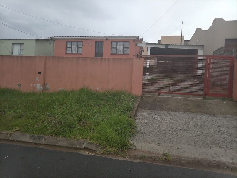 Front exterior view of a residential property featuring a perimeter wall, sliding gate, and a carport with a concrete driveway.