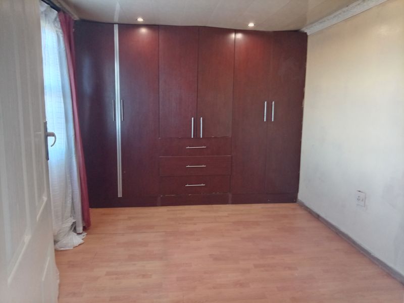 A bedroom featuring laminate flooring, recessed ceiling lighting, and extensive dark wood built-in cupboards providing ample storage space.