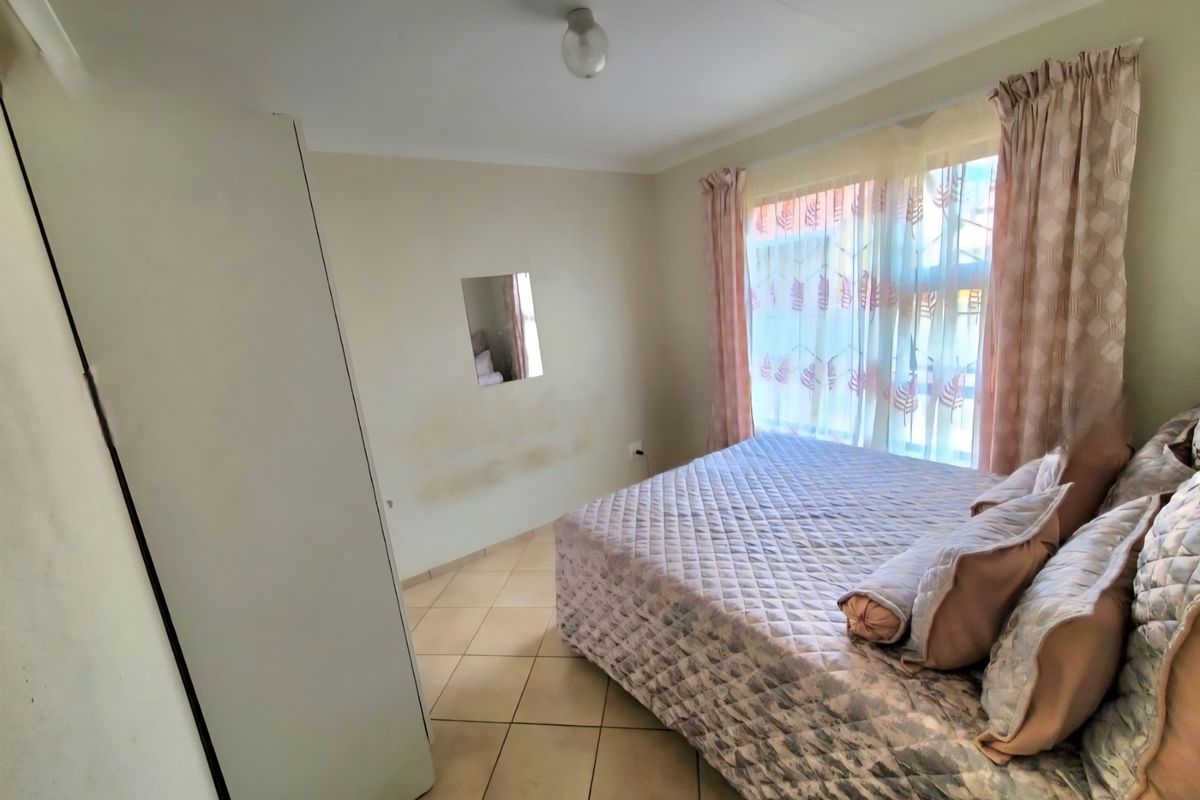 A bedroom featuring tiled flooring and a built-in wardrobe, showing visible signs of wall staining and paint wear.