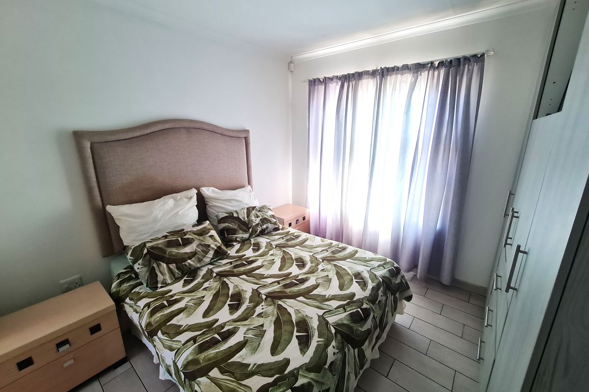 A well-maintained bedroom featuring tiled flooring, a built-in wardrobe, and neutral wall finishes, providing a clean and functional living space.