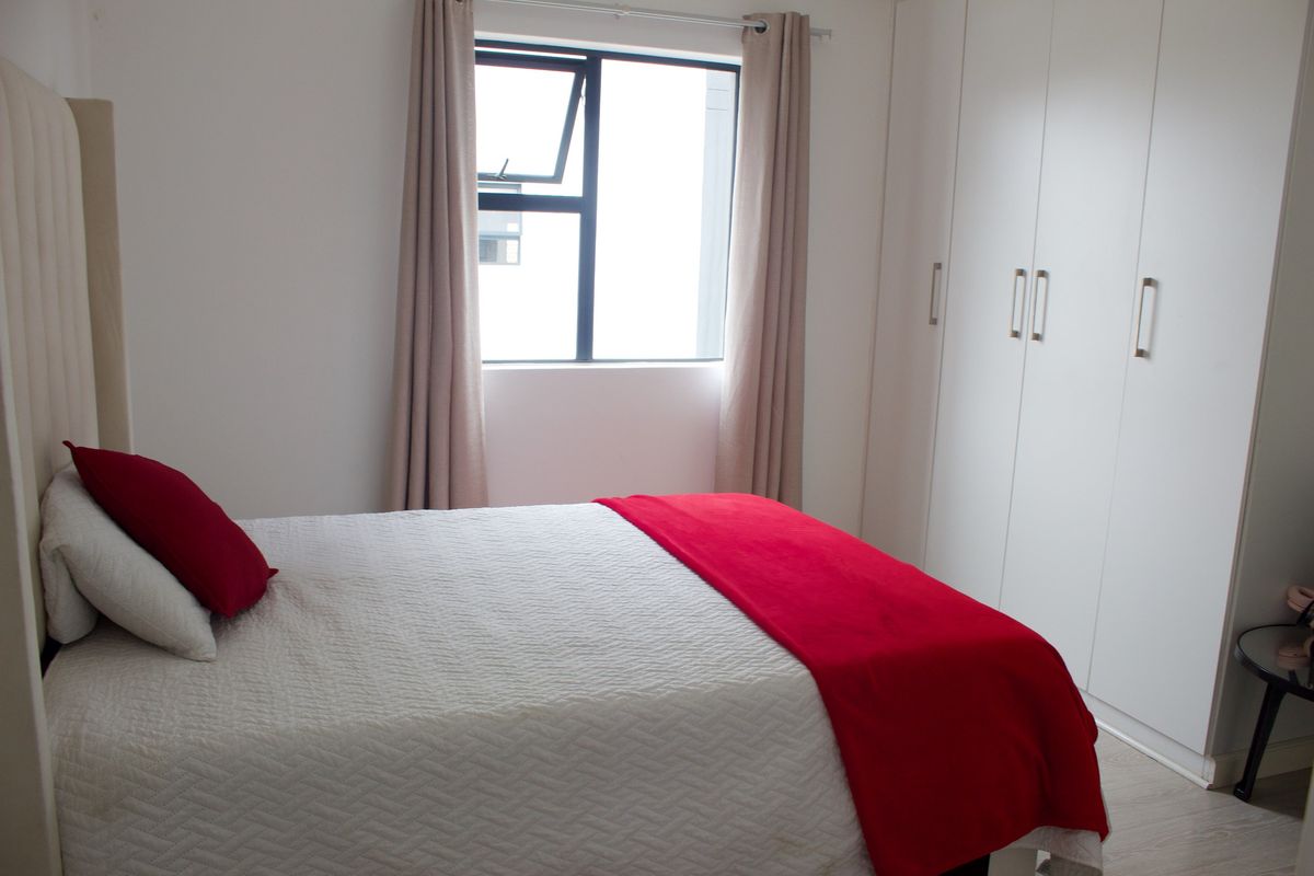 A well-maintained bedroom featuring built-in cupboards and a casement window, offering a clean and functional living space.