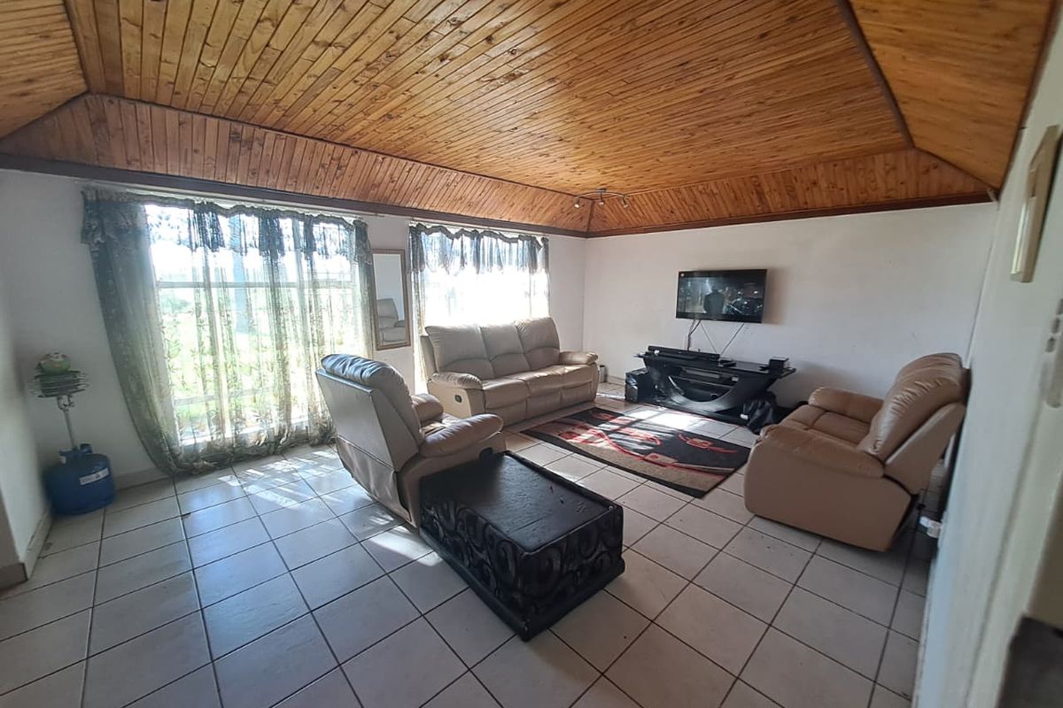 Spacious living room featuring a distinctive timber-clad vaulted ceiling and ceramic tiled flooring, offering a comfortable area for relaxation.