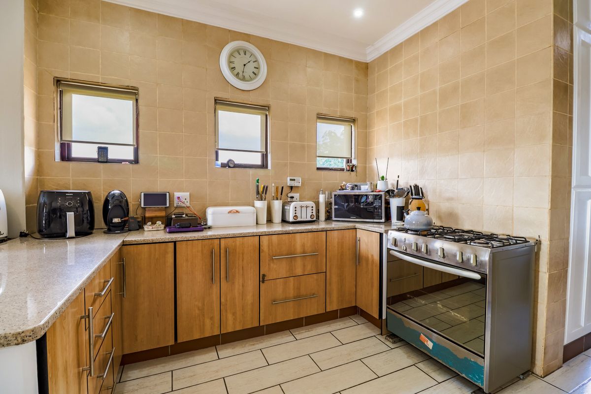 A functional kitchen featuring wooden cabinetry, stone-look countertops, tiled walls, and a freestanding gas stove with an oven.
