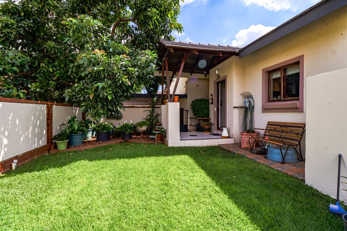 A private rear garden featuring a small lawn, a covered patio area, and perimeter boundary walls.