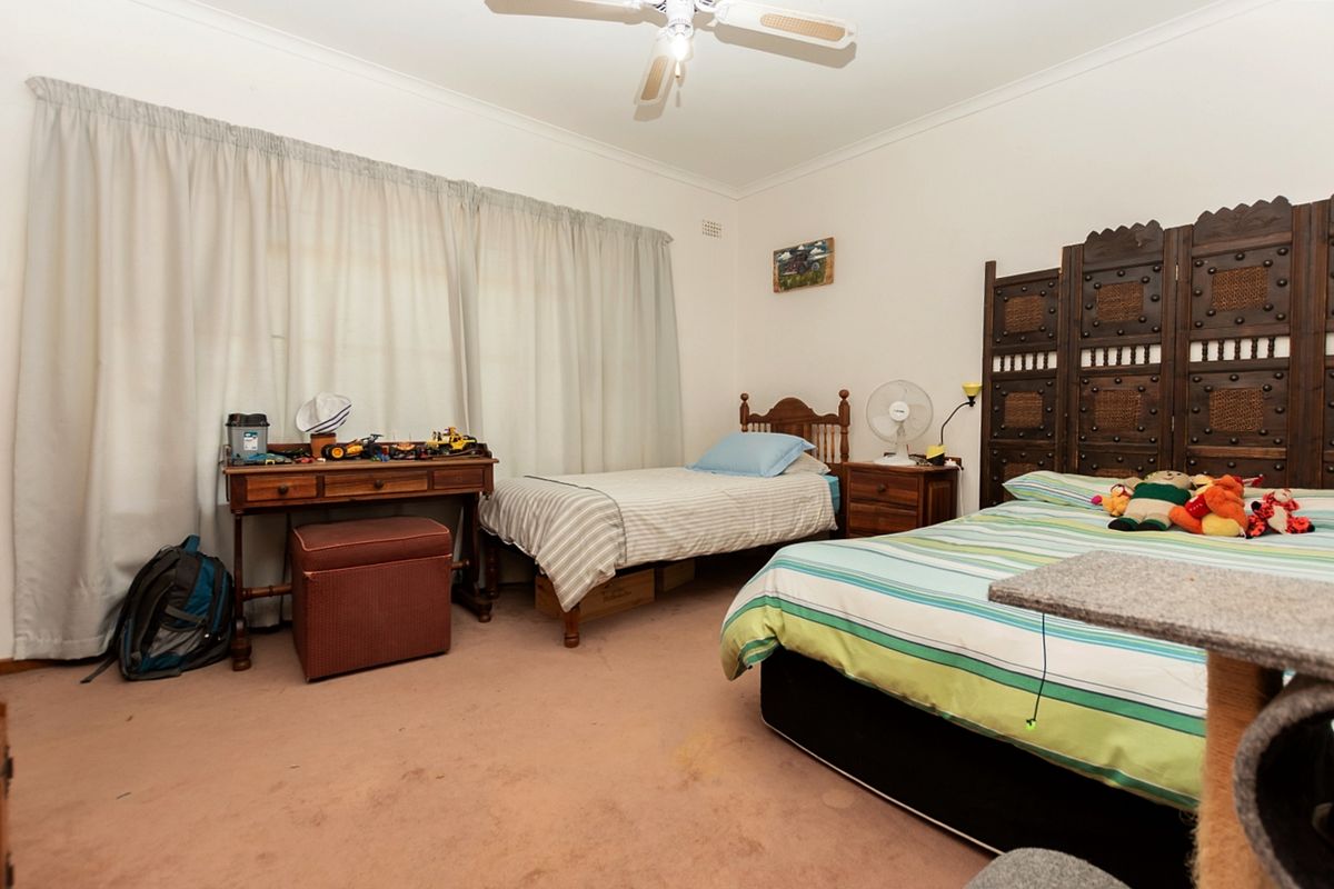 A spacious bedroom featuring neutral walls, a ceiling fan, and large windows with curtains, providing a comfortable and functional living space.