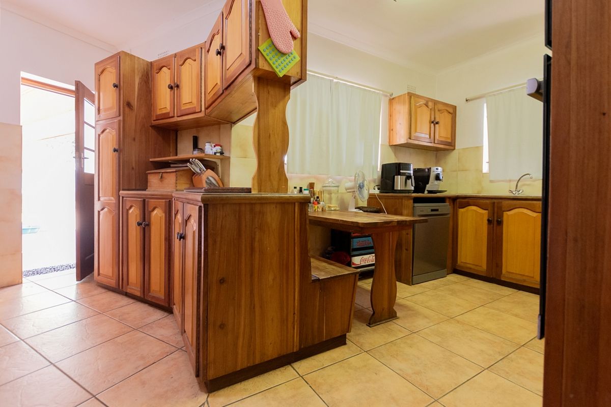 A functional kitchen featuring traditional timber cabinetry, tiled flooring, and a built-in breakfast nook, with direct access to the exterior.