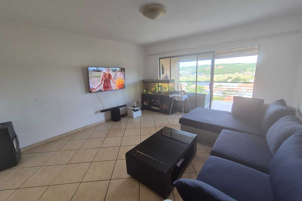 A living room featuring tiled flooring and large sliding glass doors that provide natural light and access to the balcony.