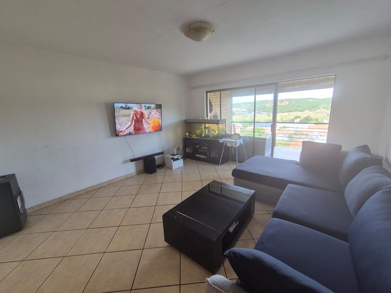 A living room featuring tiled flooring and large sliding glass doors that provide natural light and access to the balcony.