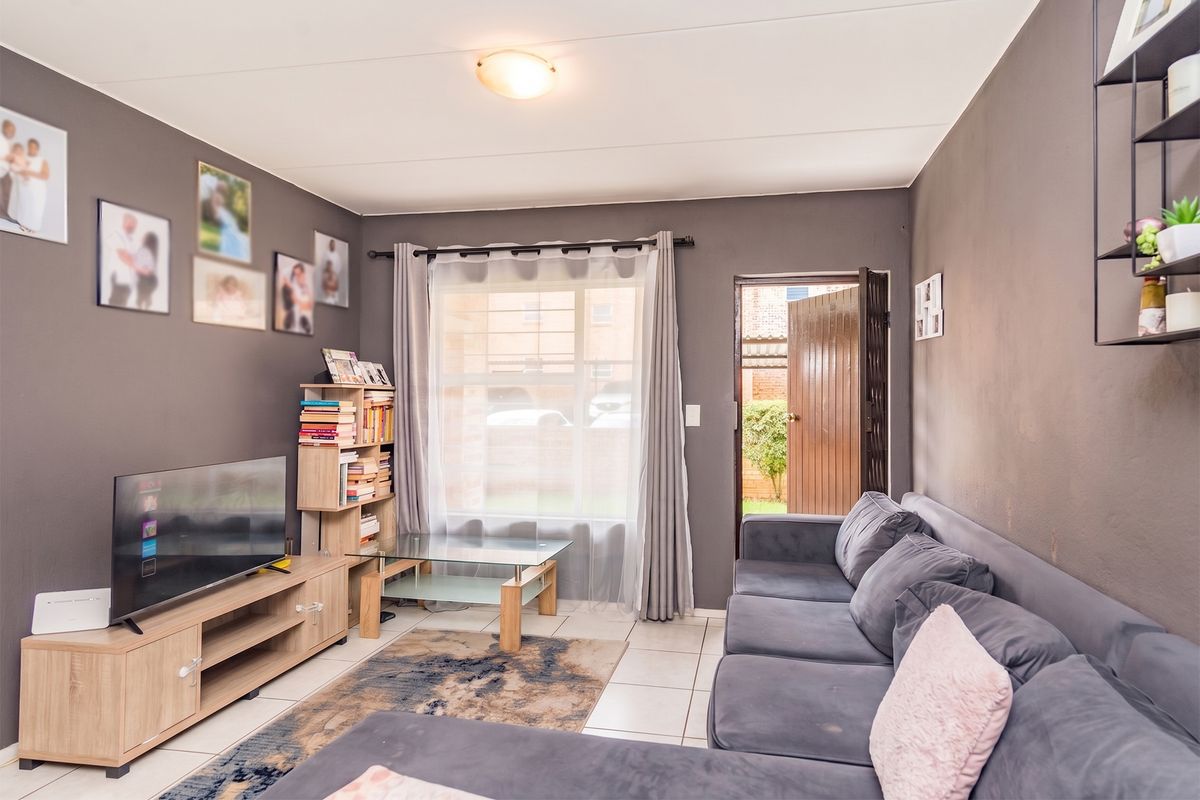 A comfortable living room featuring tiled flooring and direct access to an outdoor area, providing a functional and well-lit space.