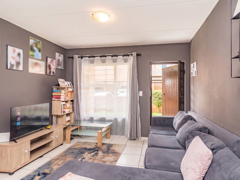 A comfortable living room featuring tiled flooring and direct access to an outdoor area, providing a functional and well-lit space.
