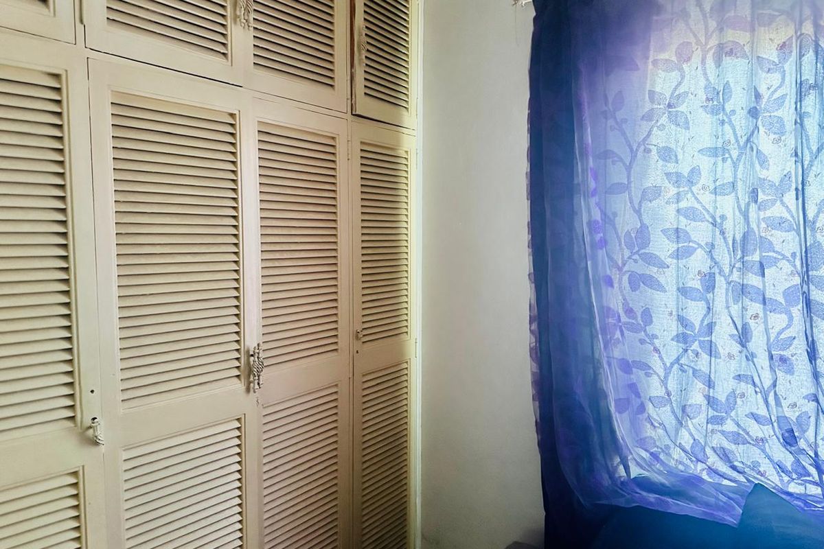 A bedroom featuring built-in floor-to-ceiling louvered door wardrobes providing ample storage space.