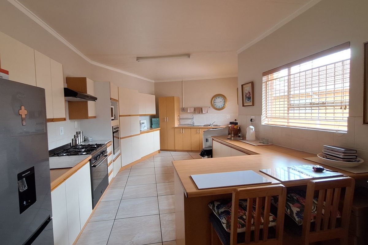 Spacious kitchen featuring extensive built-in cabinetry, gas hob, integrated oven, and a breakfast bar area with tiled flooring throughout.