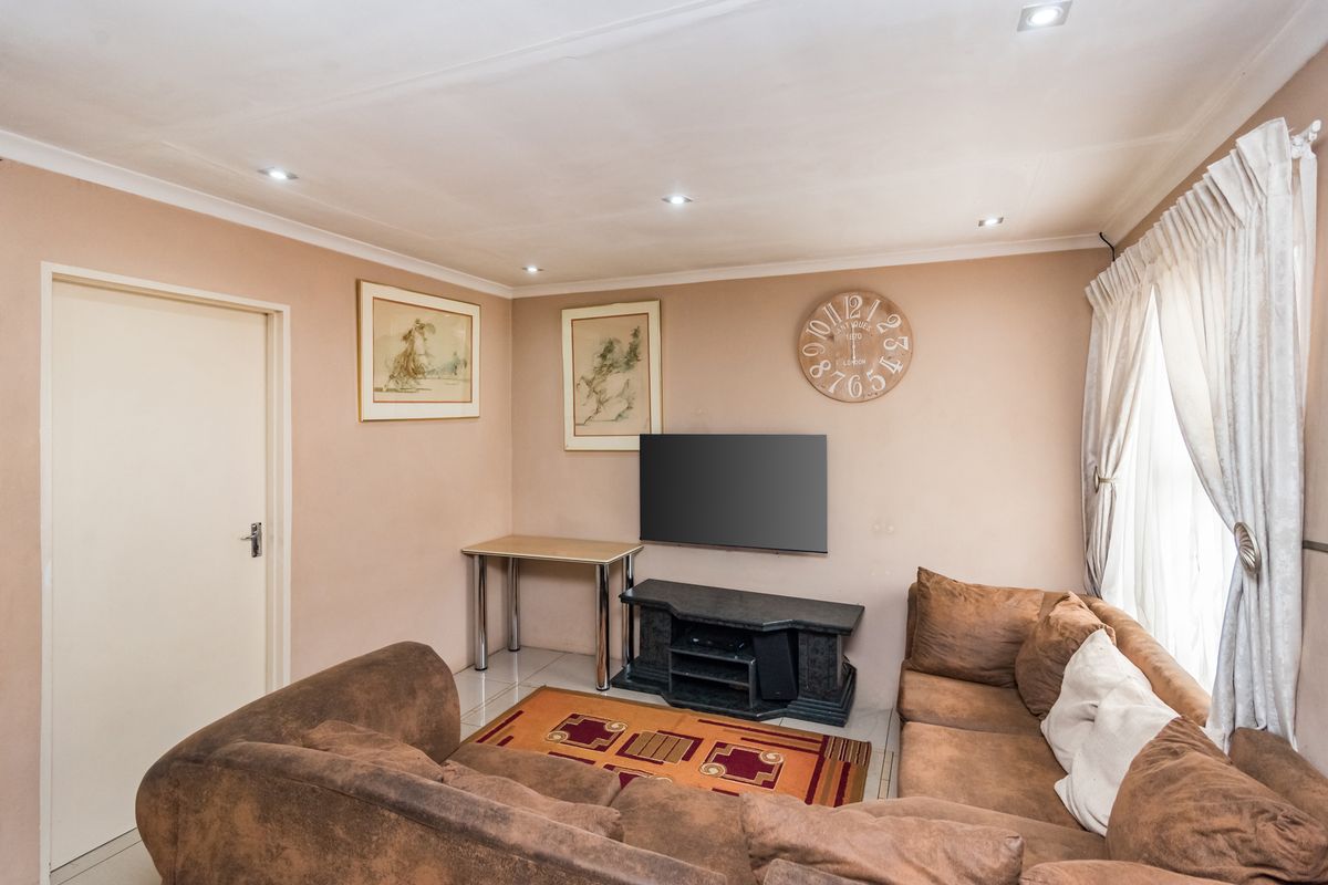 A comfortable living room featuring tiled flooring, recessed downlighting, and coved ceiling details, providing a functional and neutral space for relaxation.