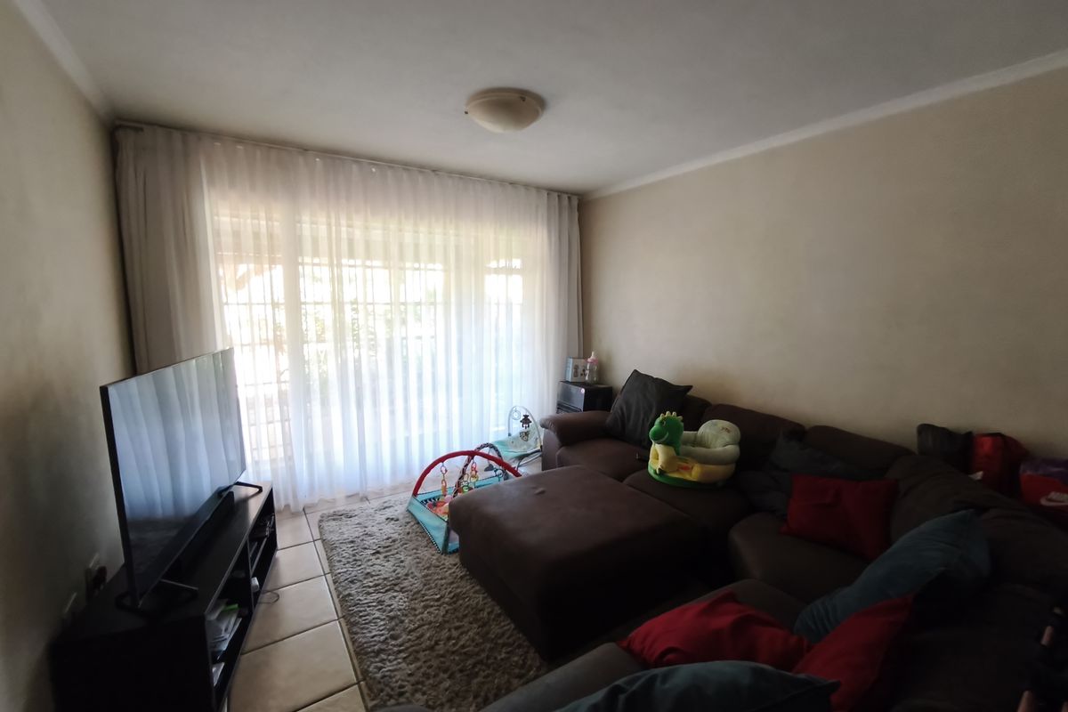 A comfortable living room featuring tiled flooring and a large sliding glass door that provides ample natural light.