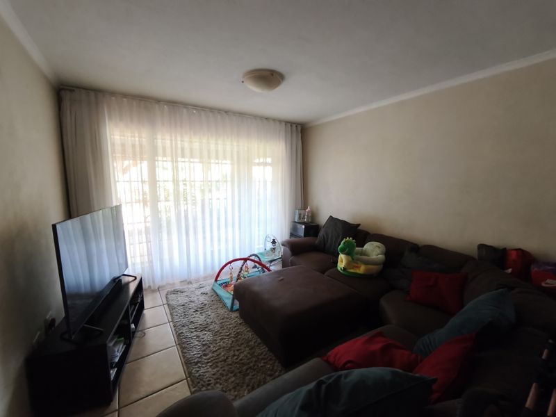 A comfortable living room featuring tiled flooring and a large sliding glass door that provides ample natural light.