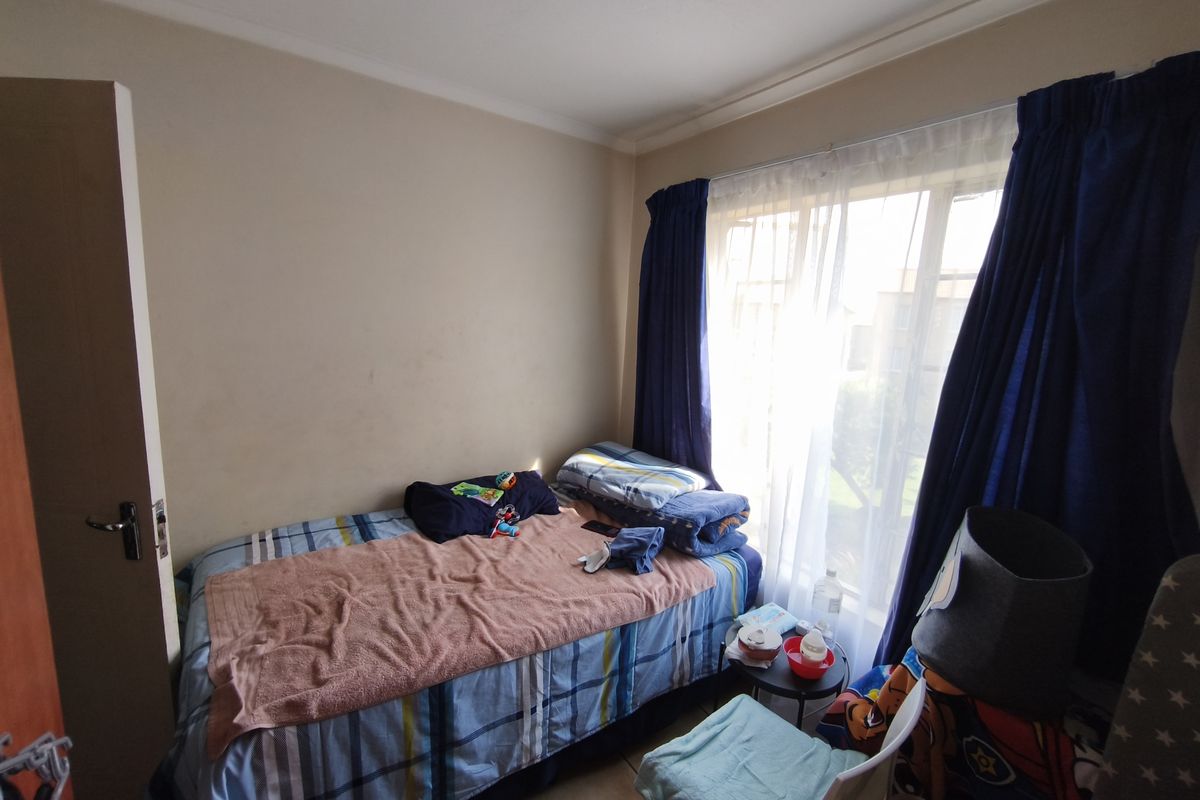 A compact bedroom featuring tiled flooring, neutral wall finishes, and a large window allowing natural light, suitable for a single bed setup.