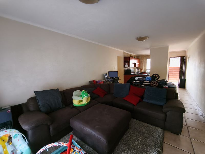 Open-plan living area featuring tiled flooring and a connected kitchen space with built-in cabinetry, offering a functional layout for daily living.