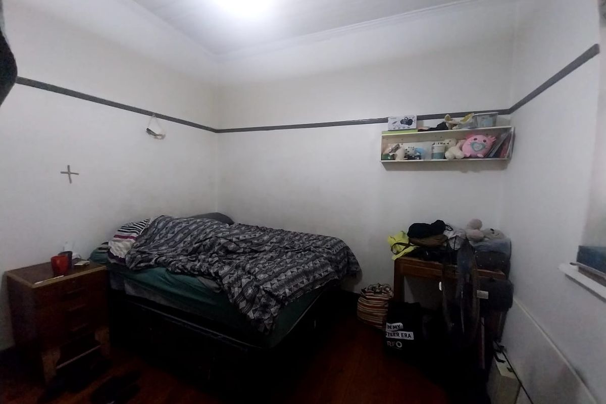 A bedroom featuring timber flooring, picture rails, and a ceiling cornice.