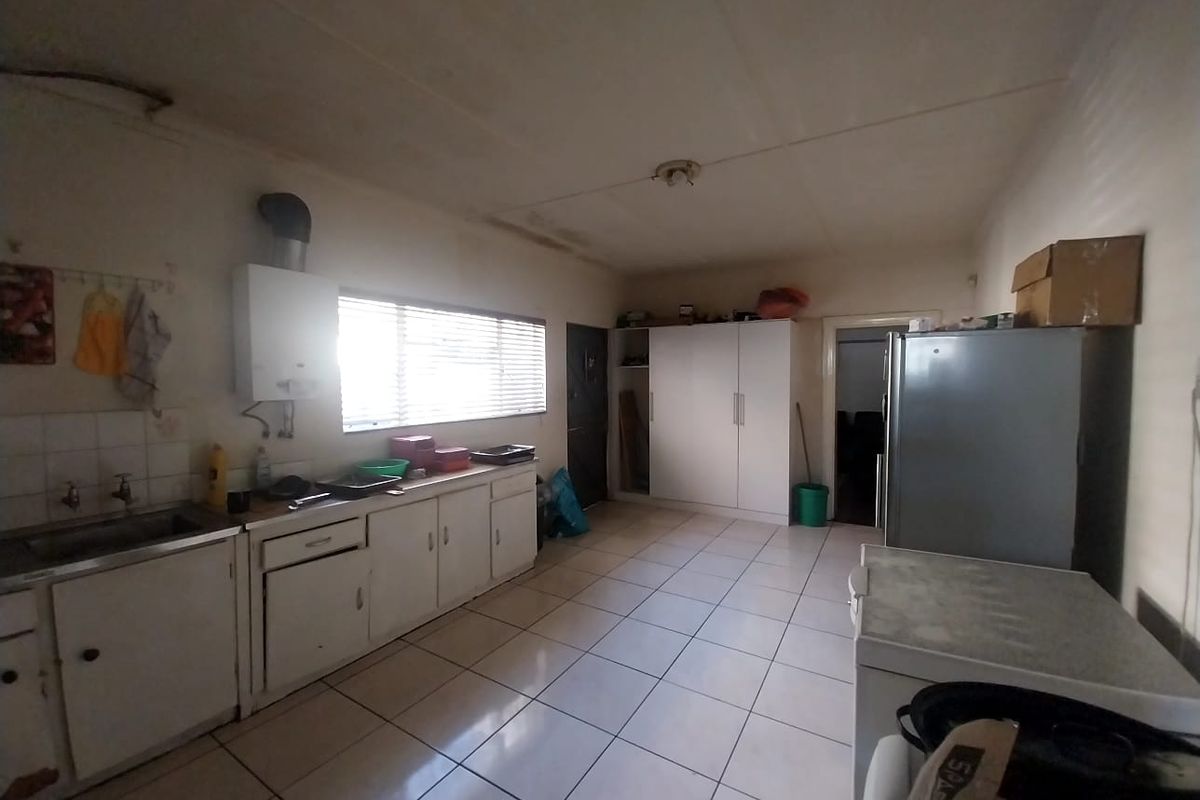 A functional kitchen space featuring tiled flooring, built-in cabinetry, a stainless steel sink, and a wall-mounted water heater.