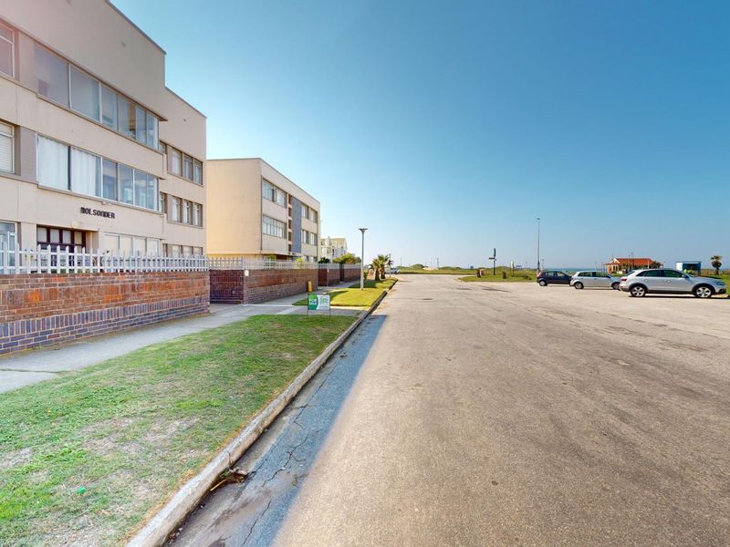 Street view showing the exterior facade of the apartment building, adjacent paved road, and surrounding neighborhood landscape.
