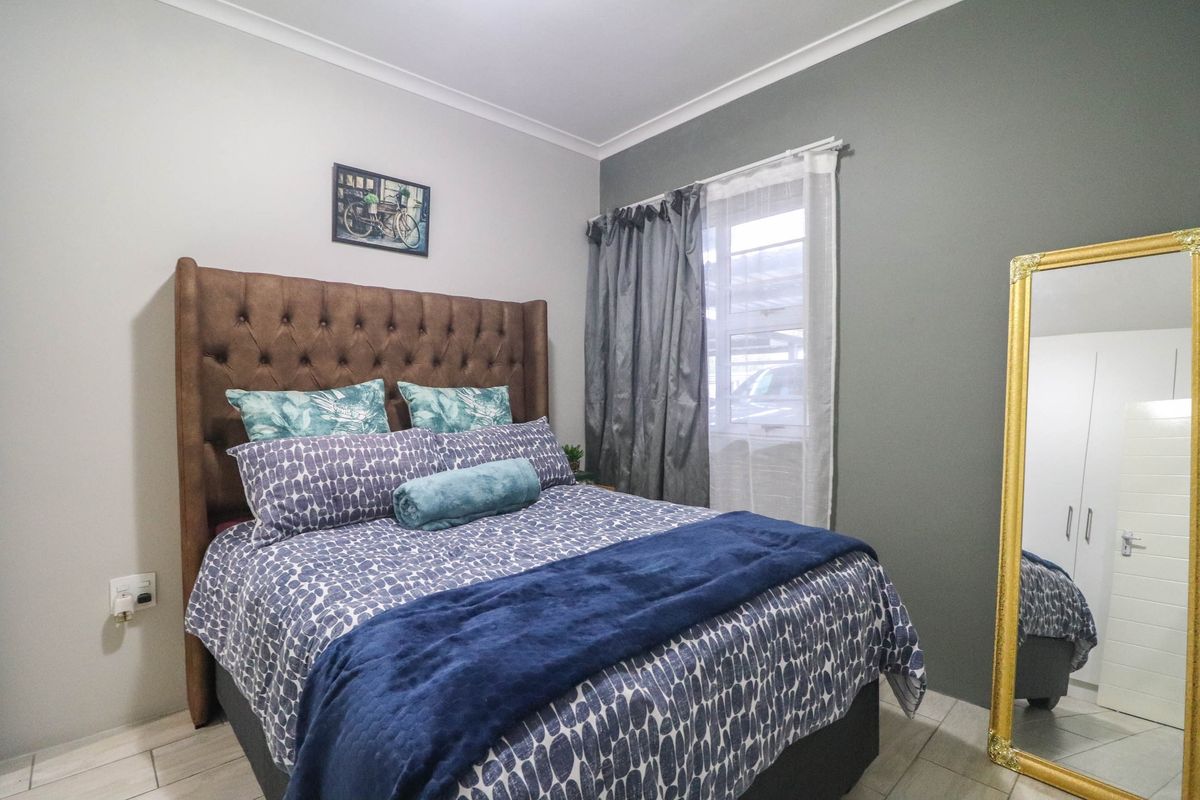 A well-maintained bedroom featuring tiled flooring, a neutral color palette with an accent wall, and built-in cupboard storage.