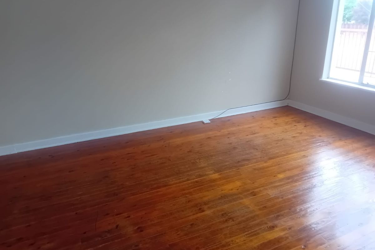 An empty bedroom featuring polished hardwood flooring and neutral wall tones, offering a blank canvas for personalization.